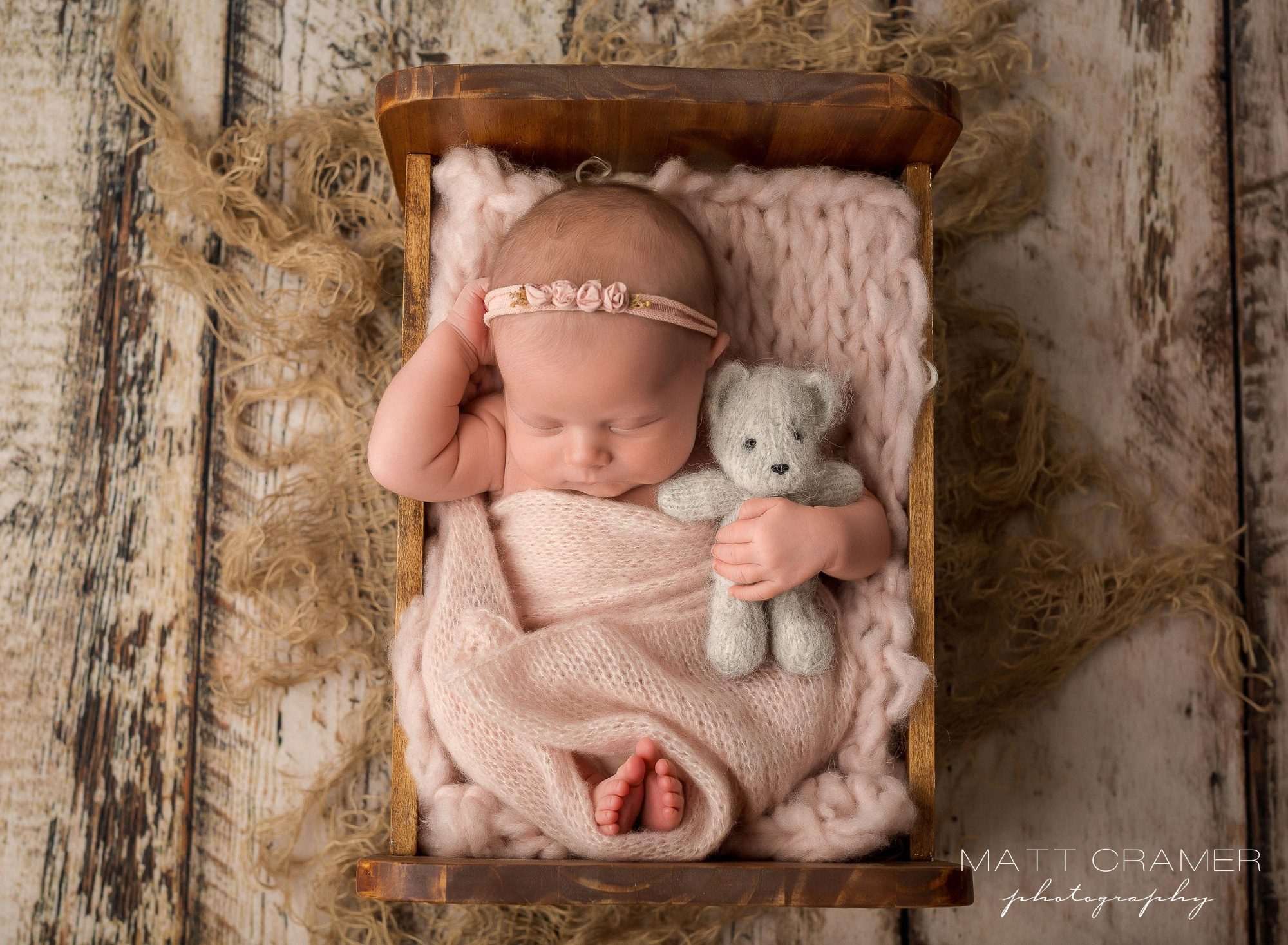 baby girl sleeping in wood newborn bed cuddling teddy bear