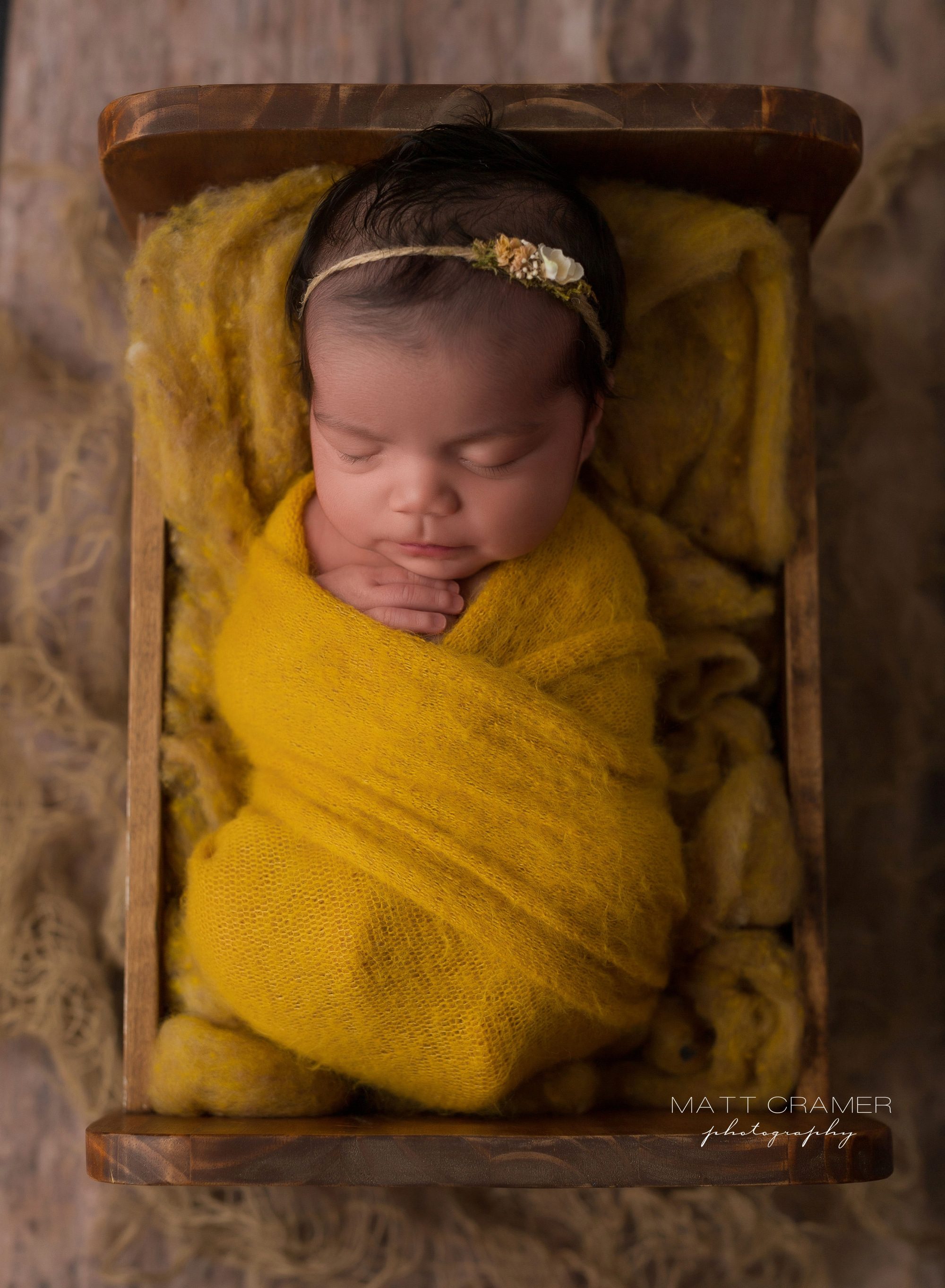 Newborn baby girl sleeping in baby bed while being photographed at her Newborn Photography in Los Angeles
