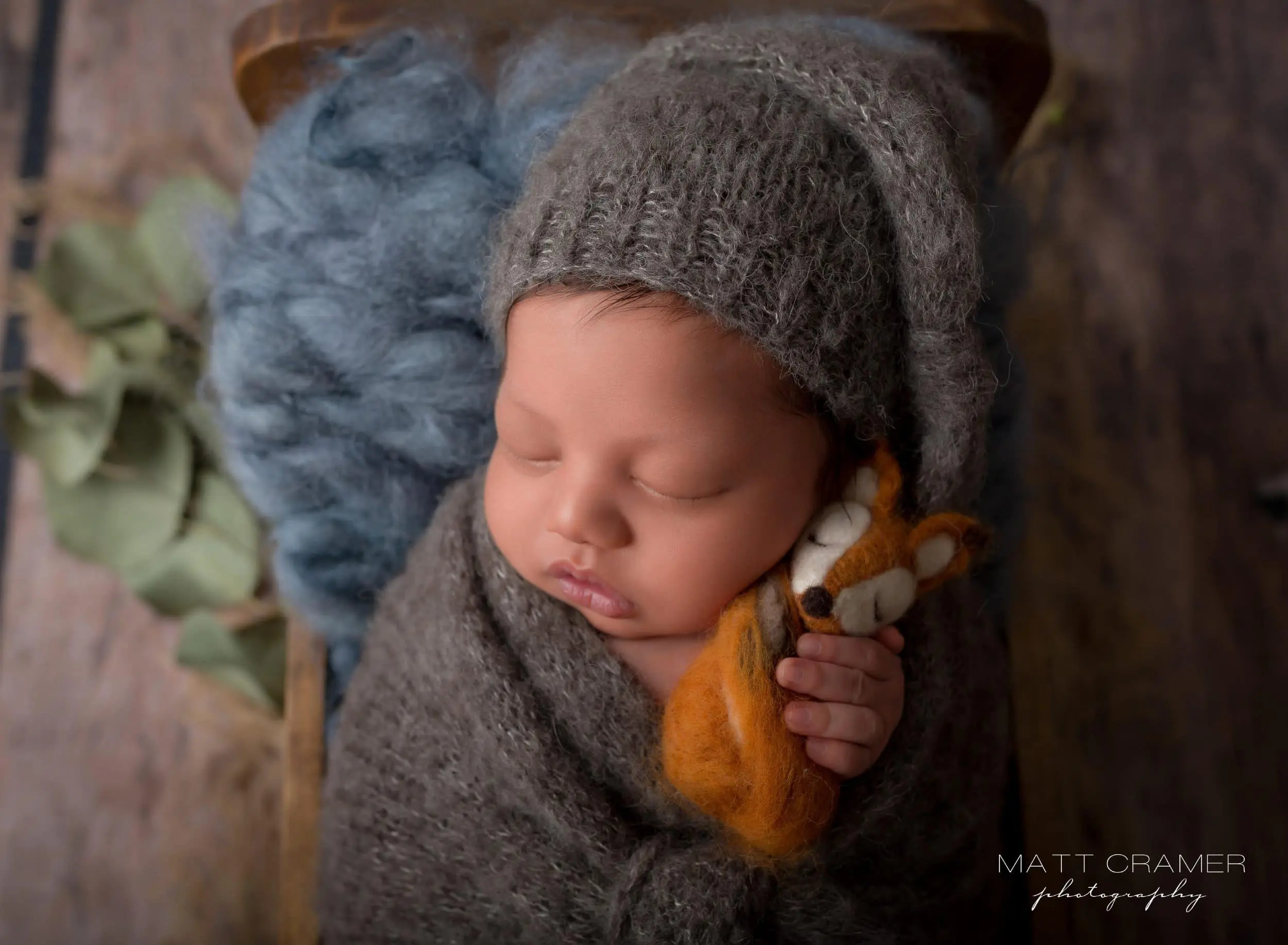 newborn baby snuggling with little fox