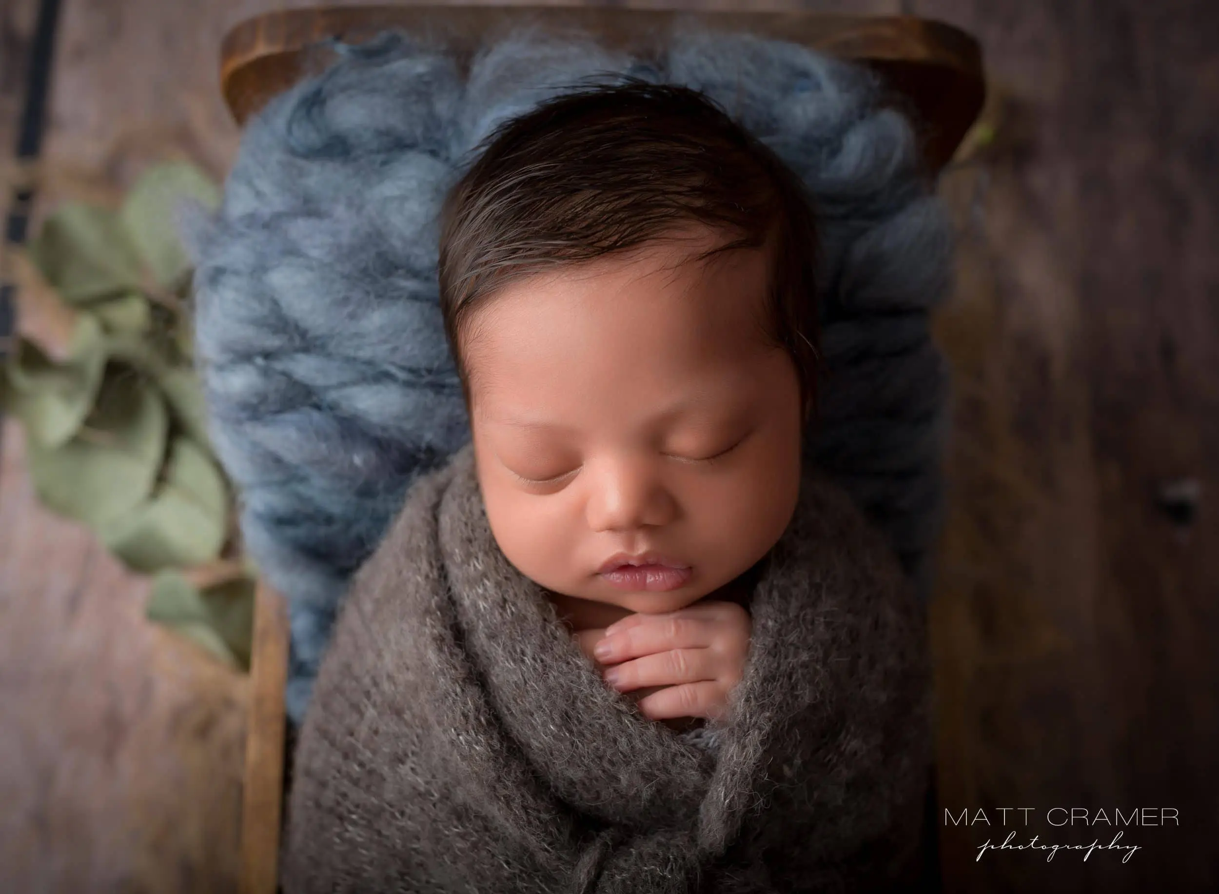 new born baby boy posed in wood baby bed prop