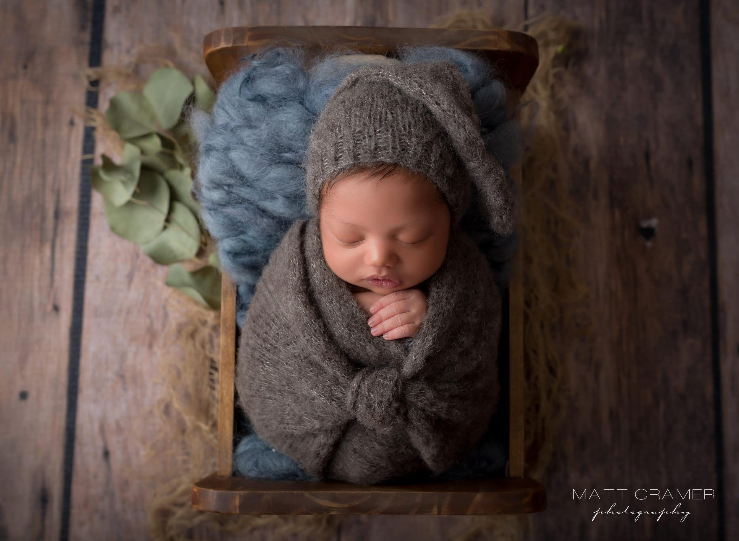 infant baby boy wearing sleepy hat during newborn photography session.