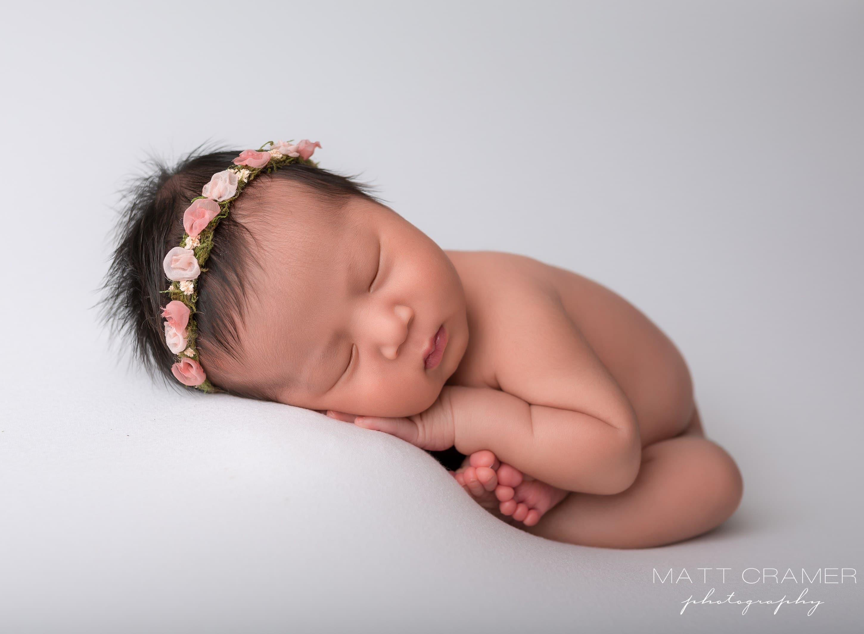 newborn baby posed on solid white fabric during a newborn photography session