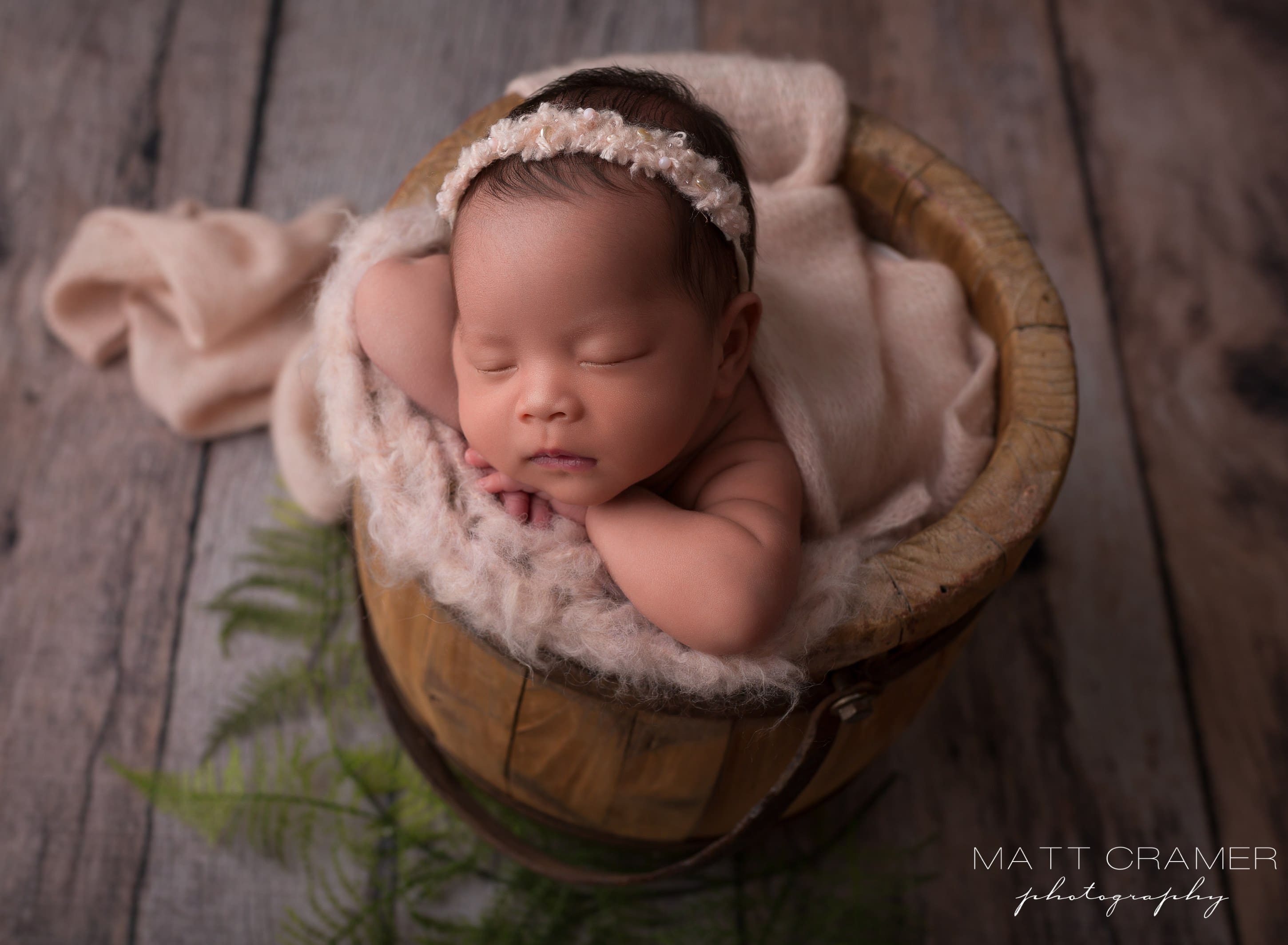 baby girl posed in a wood bucket