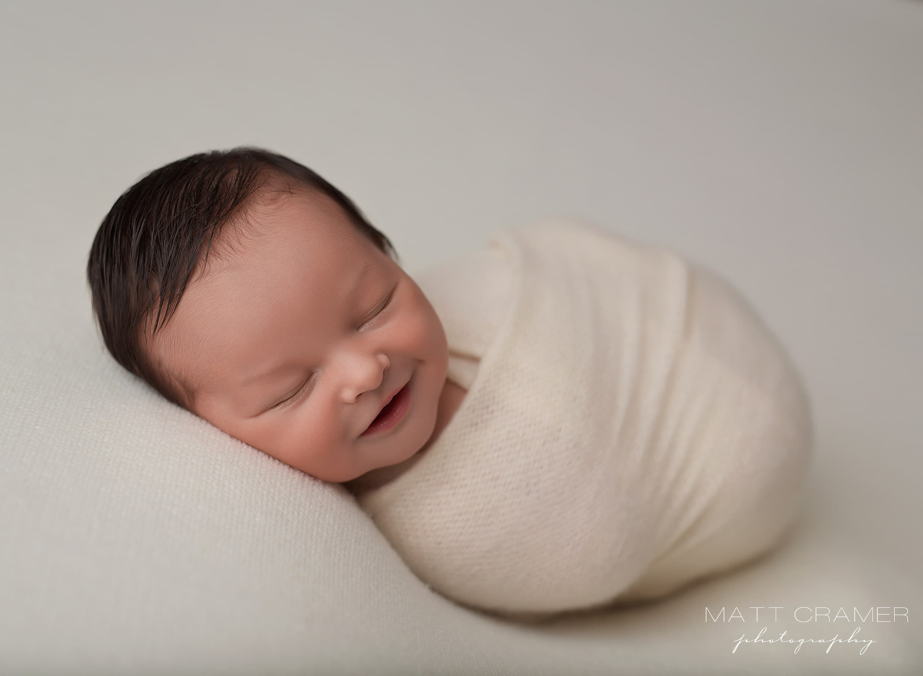 Smiling baby boy swaddled in cream wrap