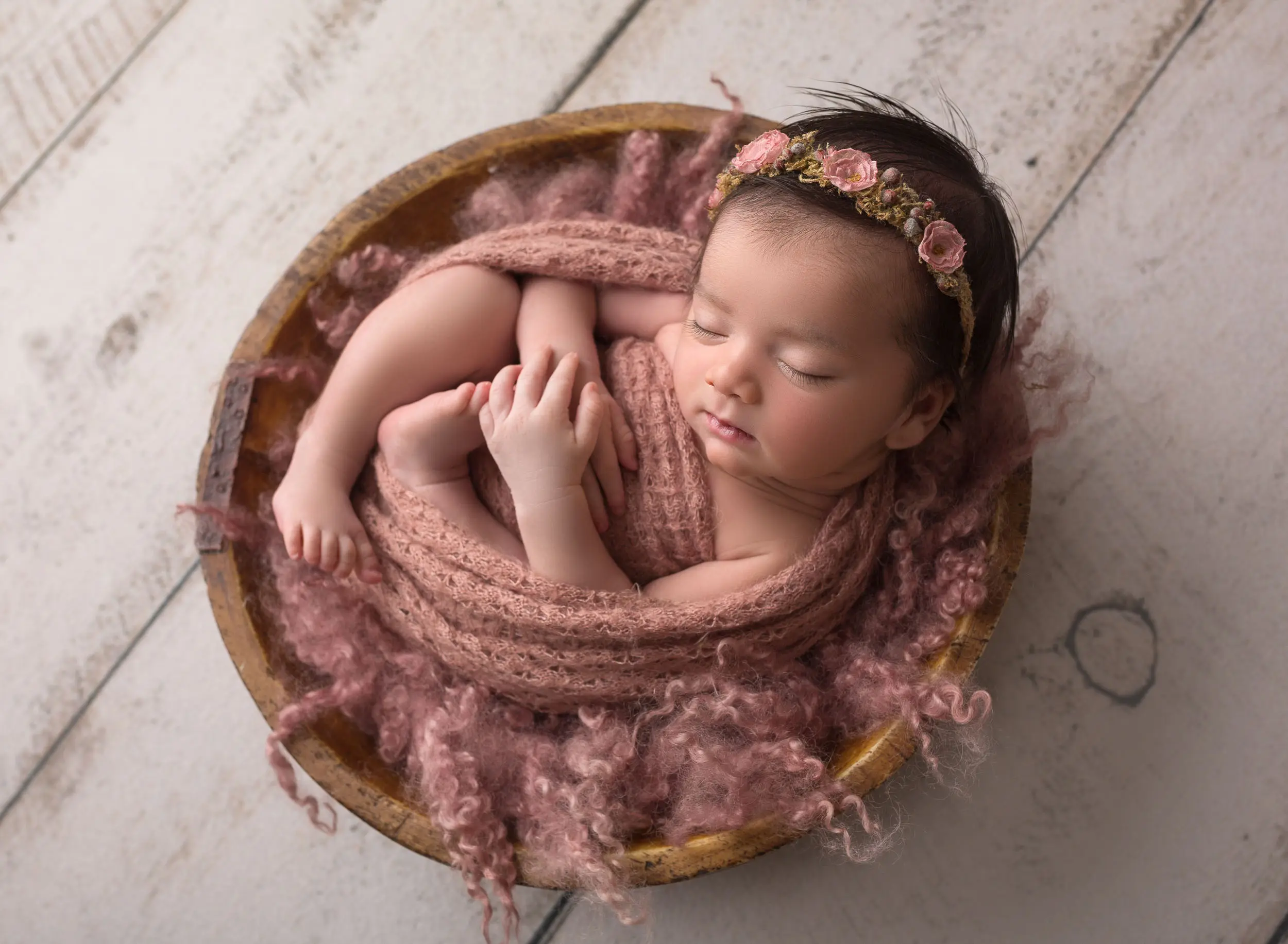 baby girl in wood bowl in newborn photography session