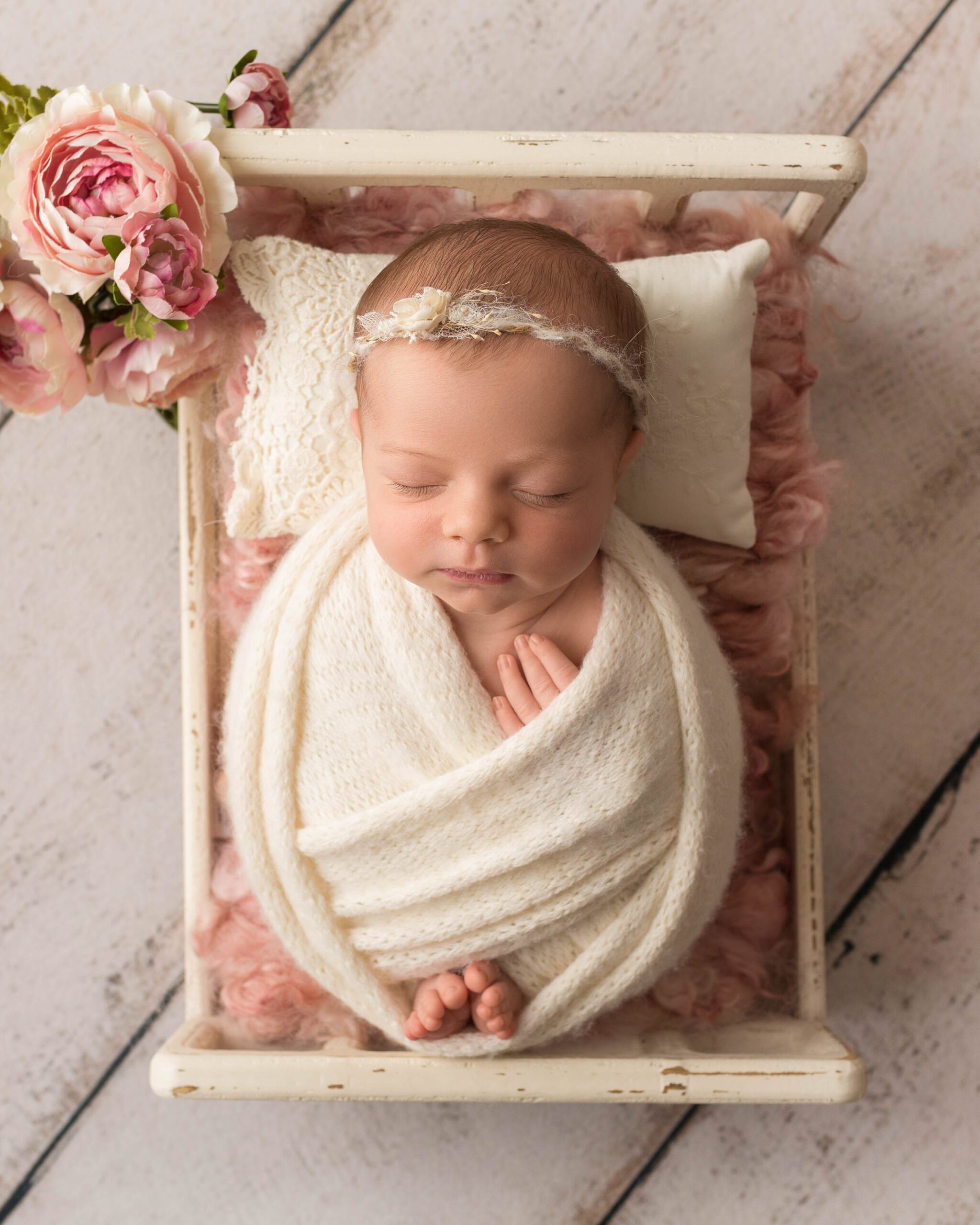  newborn baby girl in wood bed prop