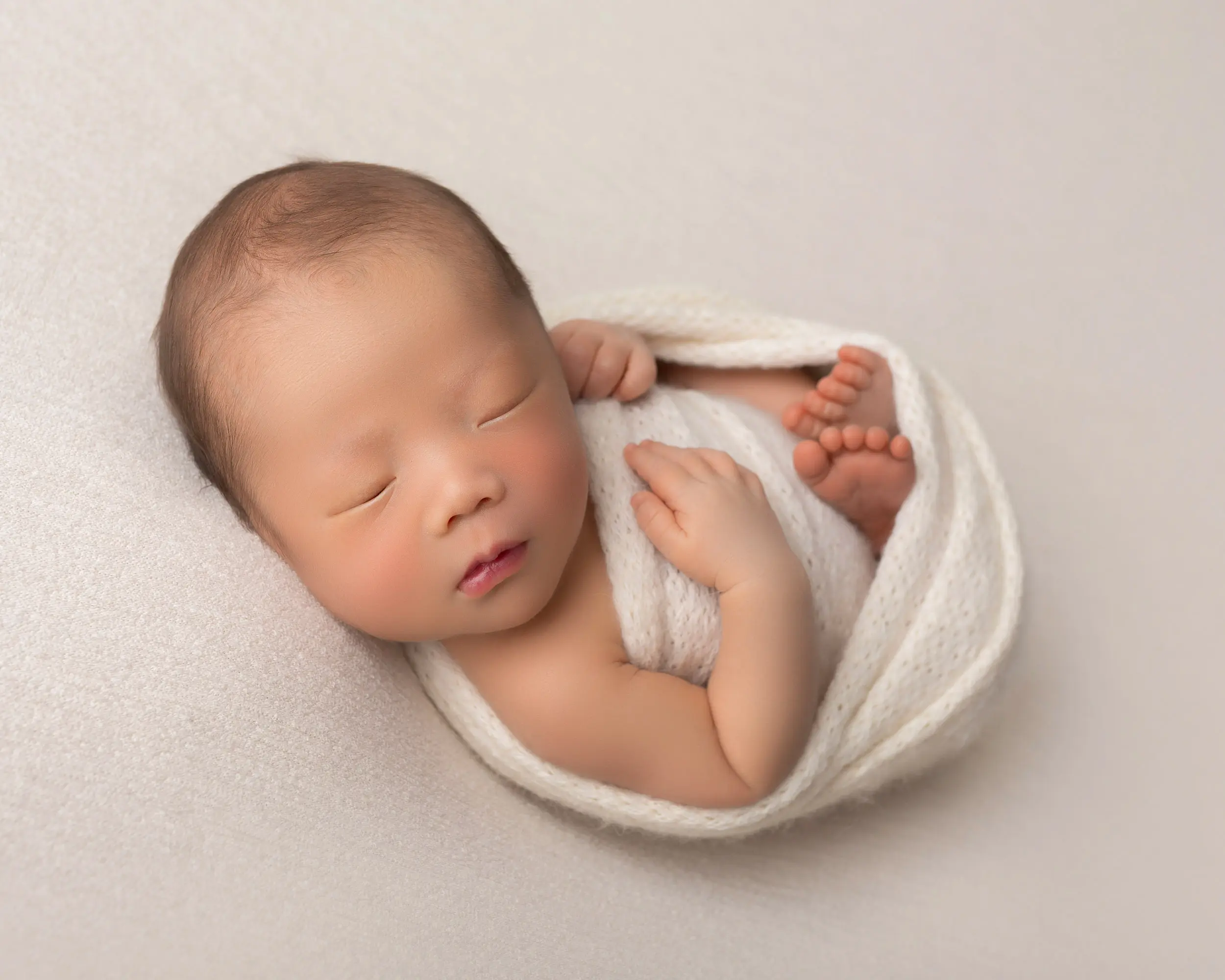 newborn baby boy in cream swaddle wrap