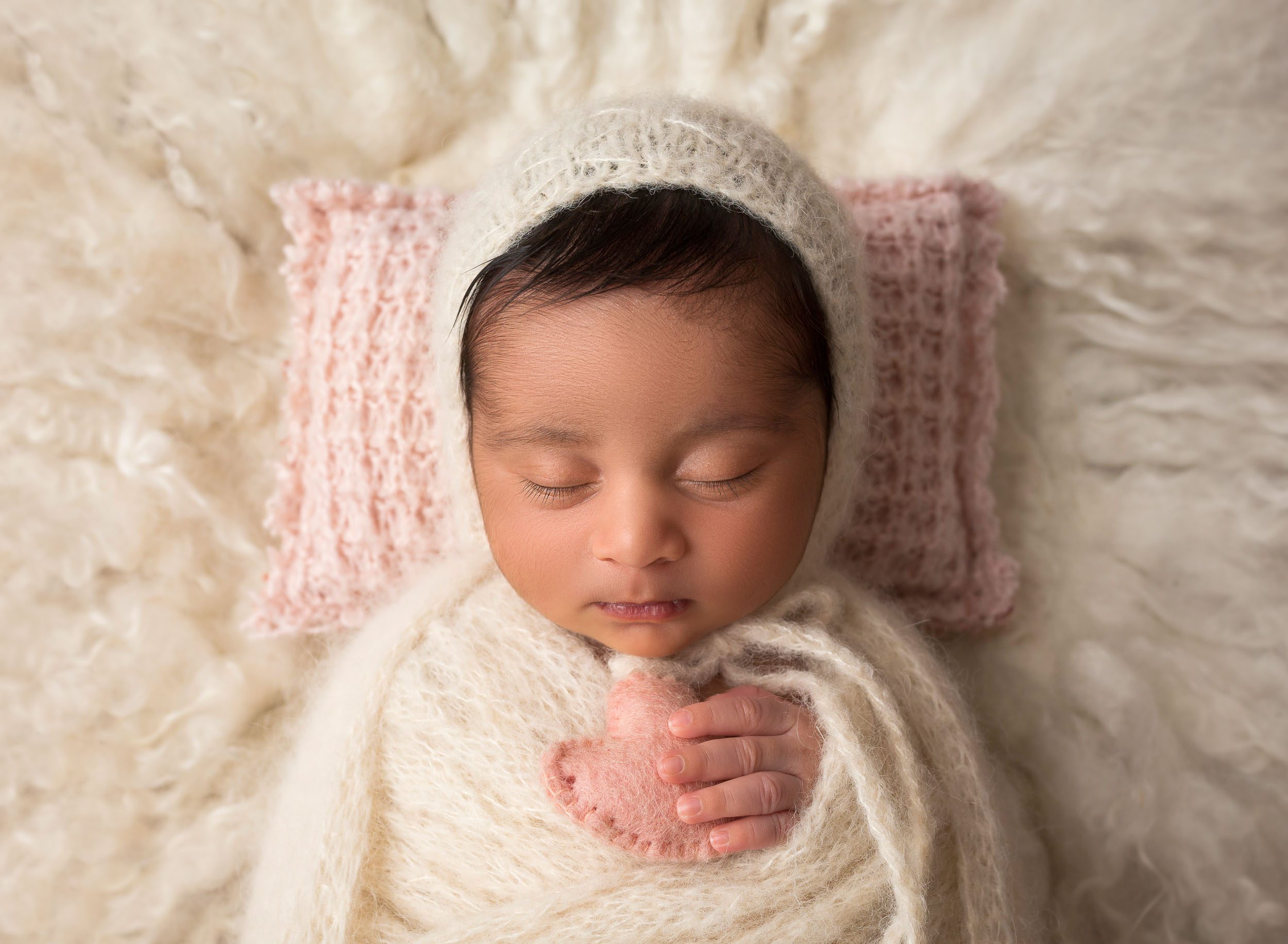 newborn baby girl wearing white knit bonnet