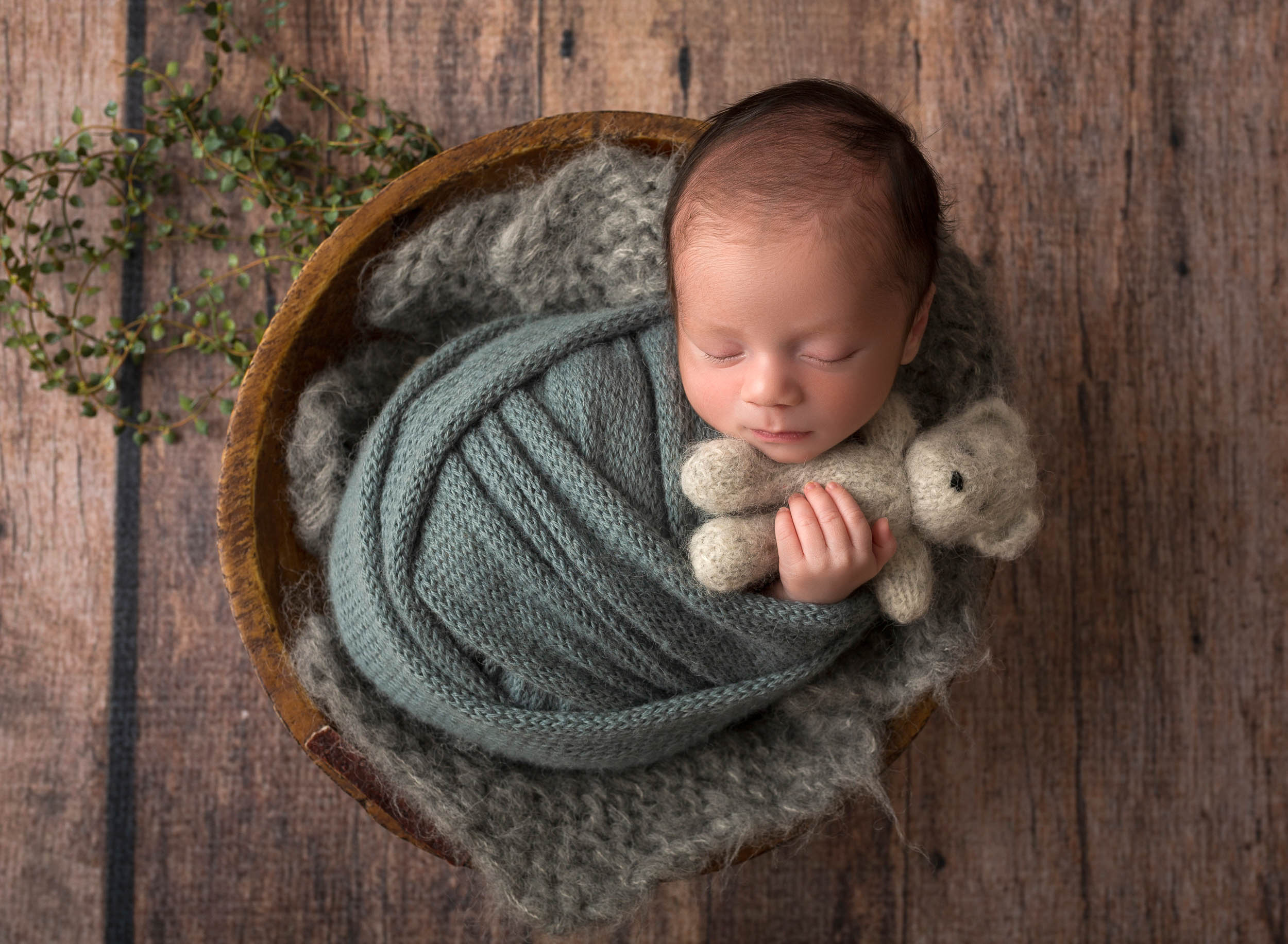 cute baby boy in blue swaddle cuddling teddy bear