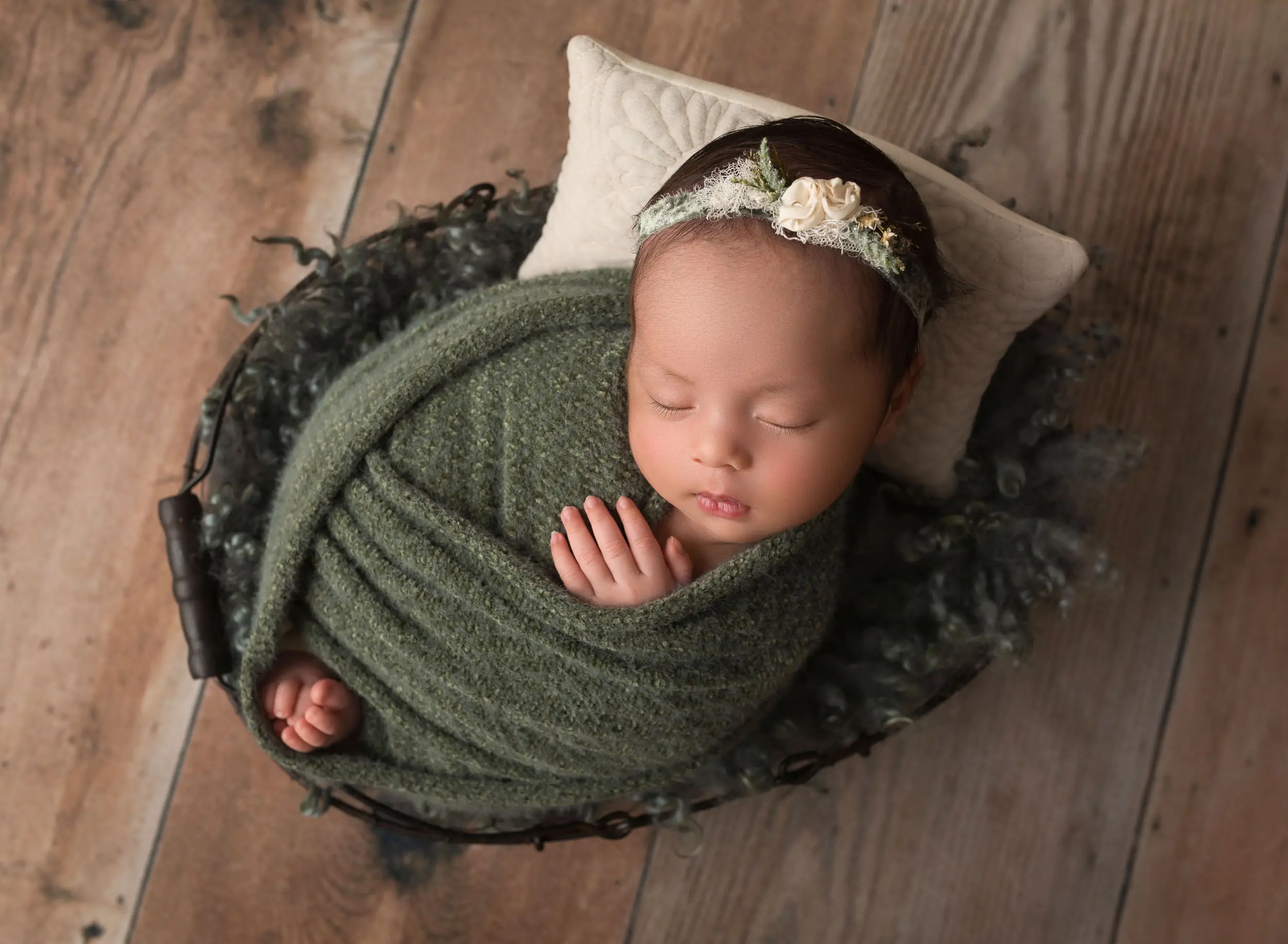 newborn baby girl swaddles in green wrap