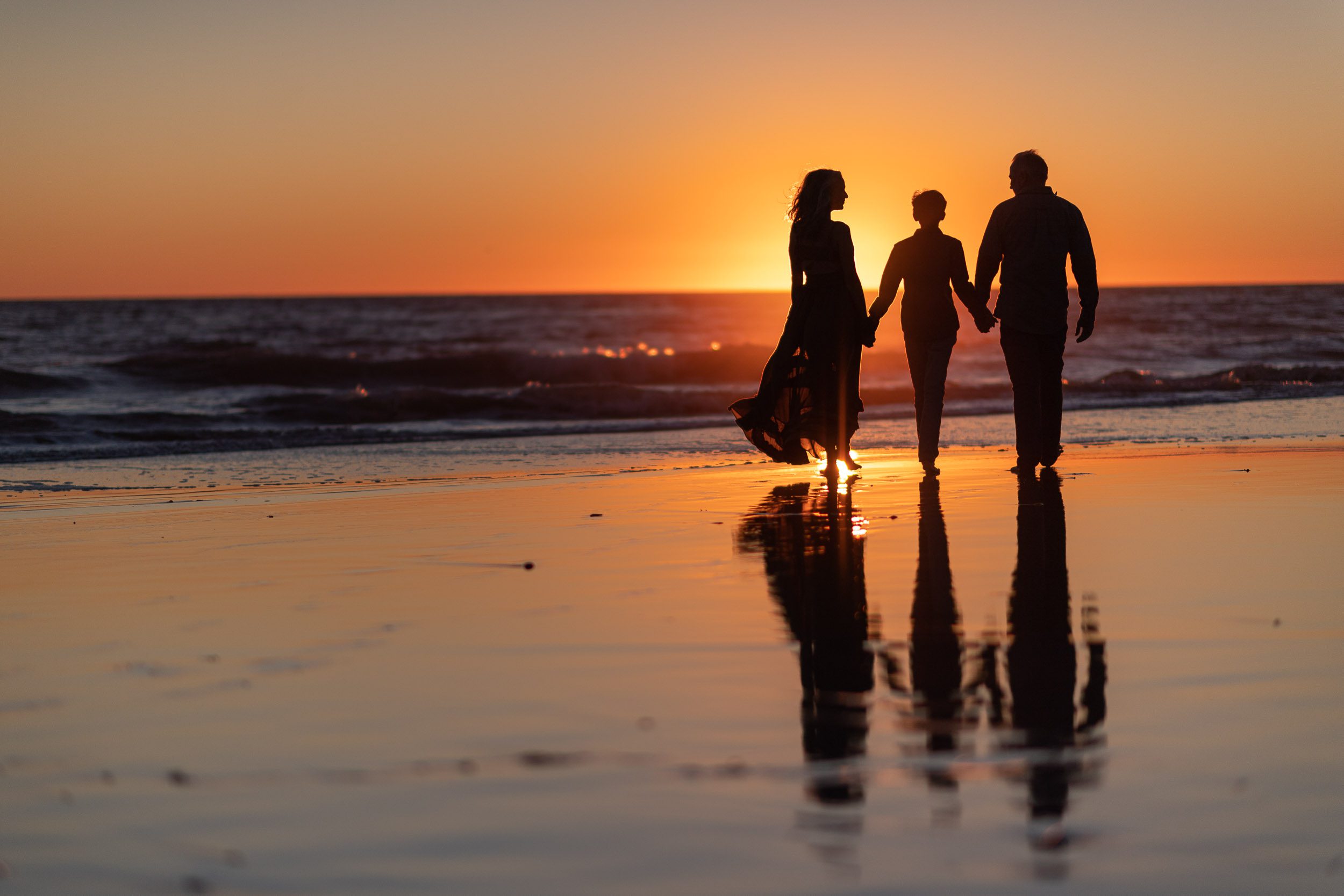 family walking on the beach at sunset
