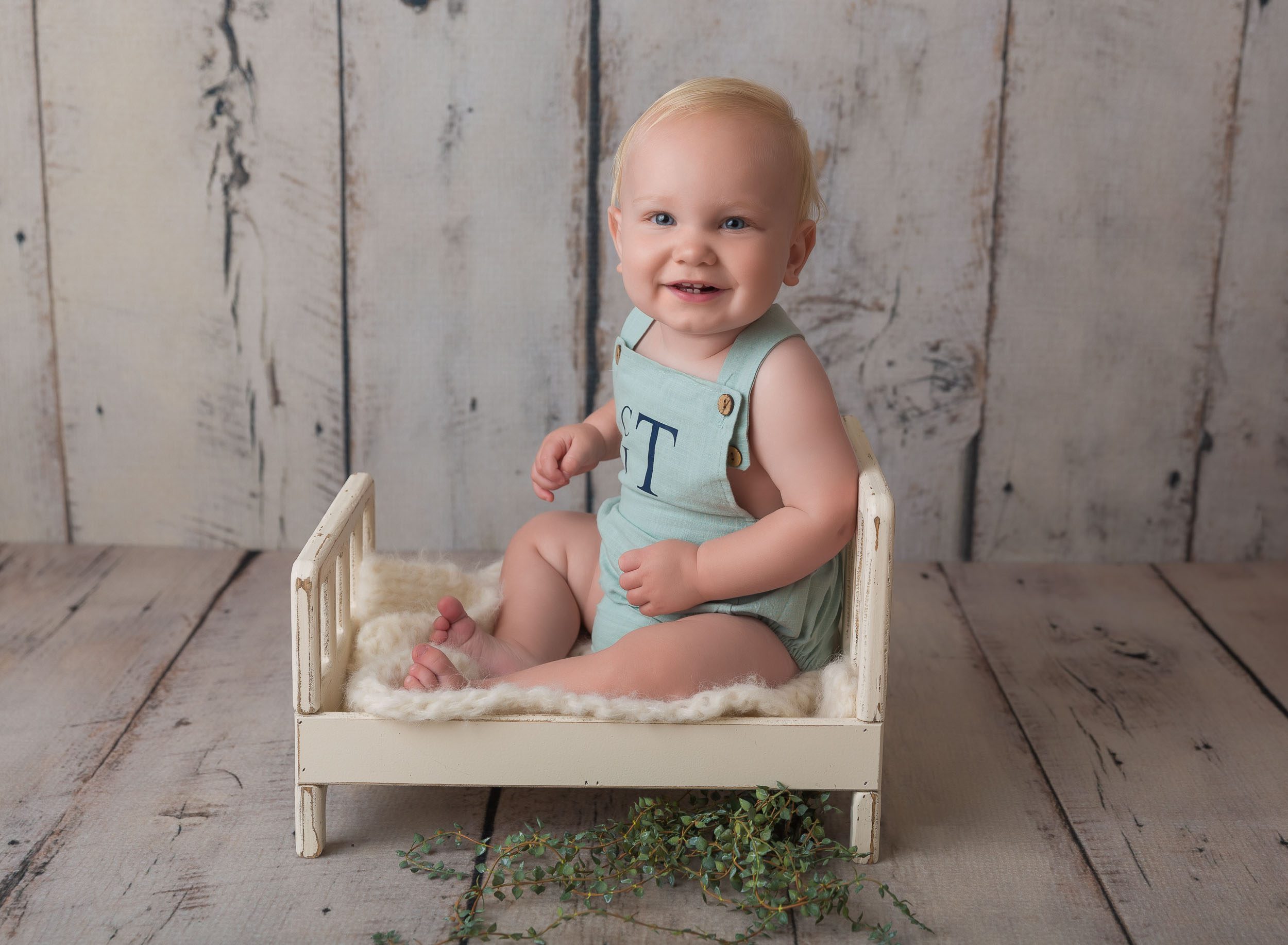 baby boy sitting in white bed prop