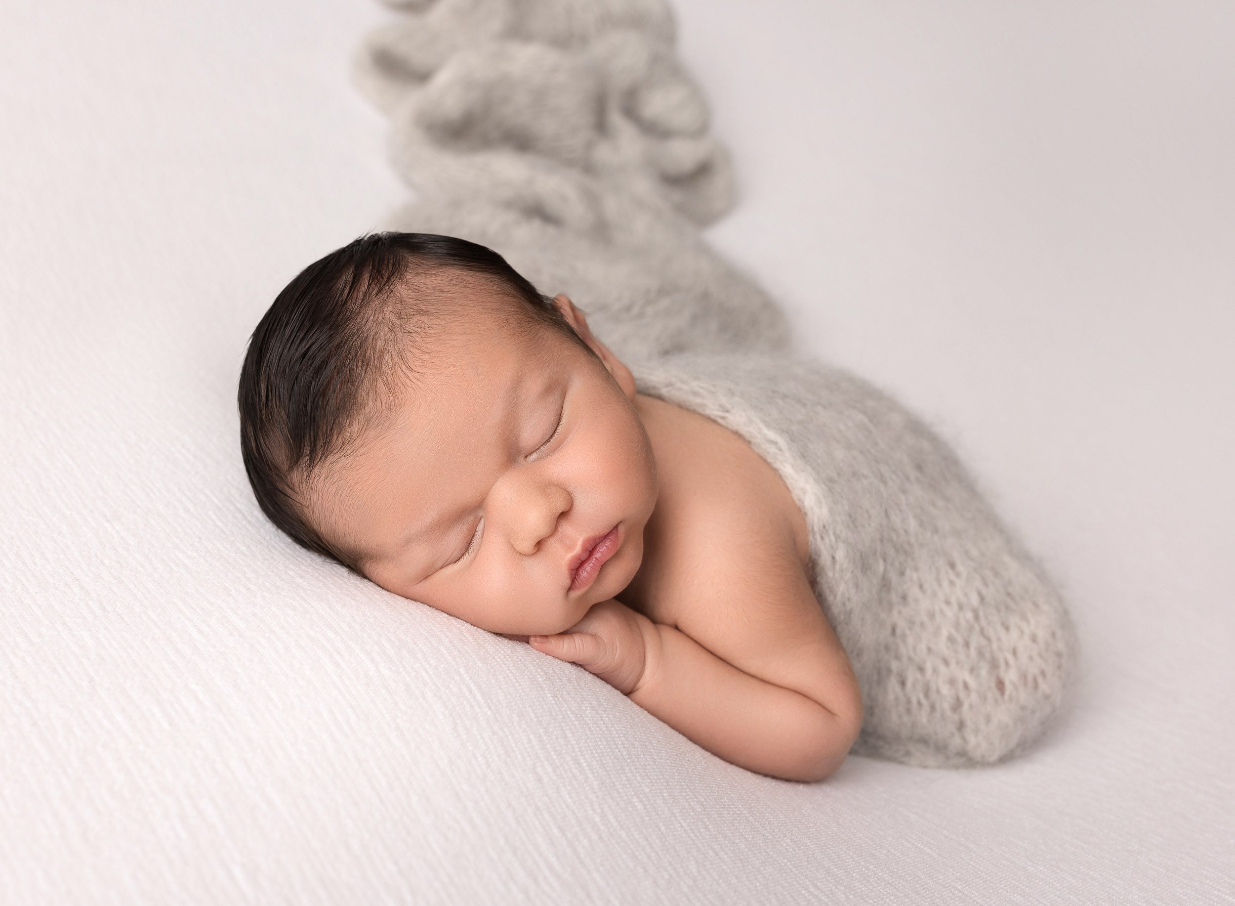 baby boy newborn laying down with grey wrap