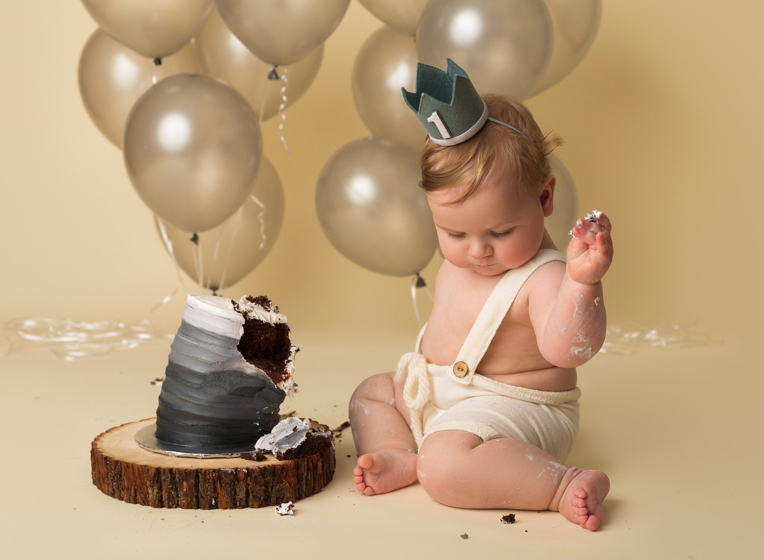 one year old baby boy with big cake and balloons