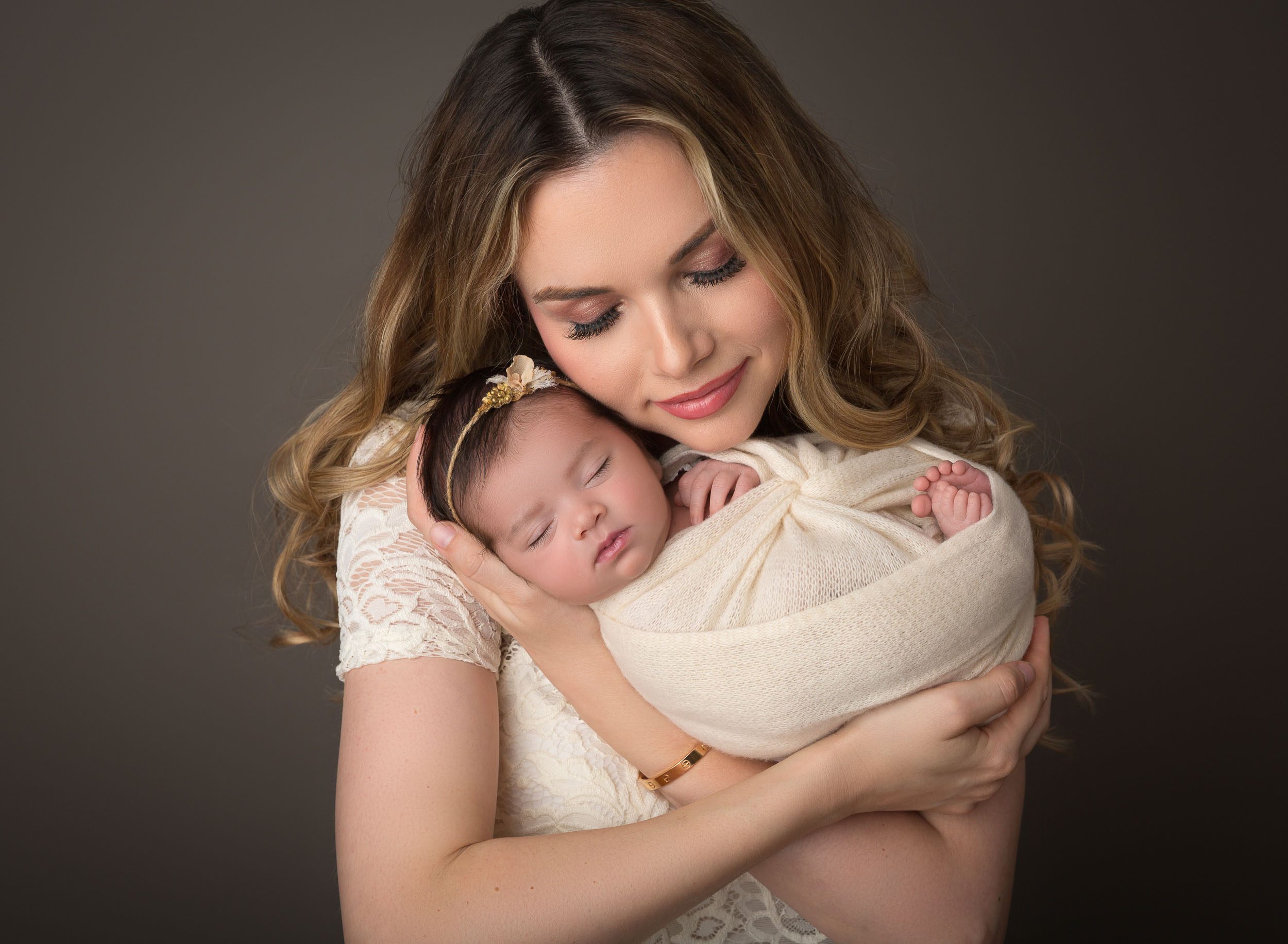 mom holding newborn baby up close to her cheek with eyes closed